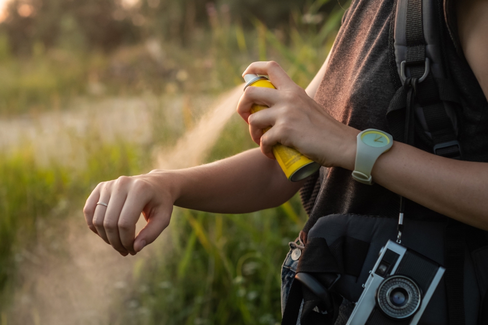 Woman using anti mosquito spray outdoors at hiking trip.  Battle of the Insect Repellents: Picaridin vs. DEET