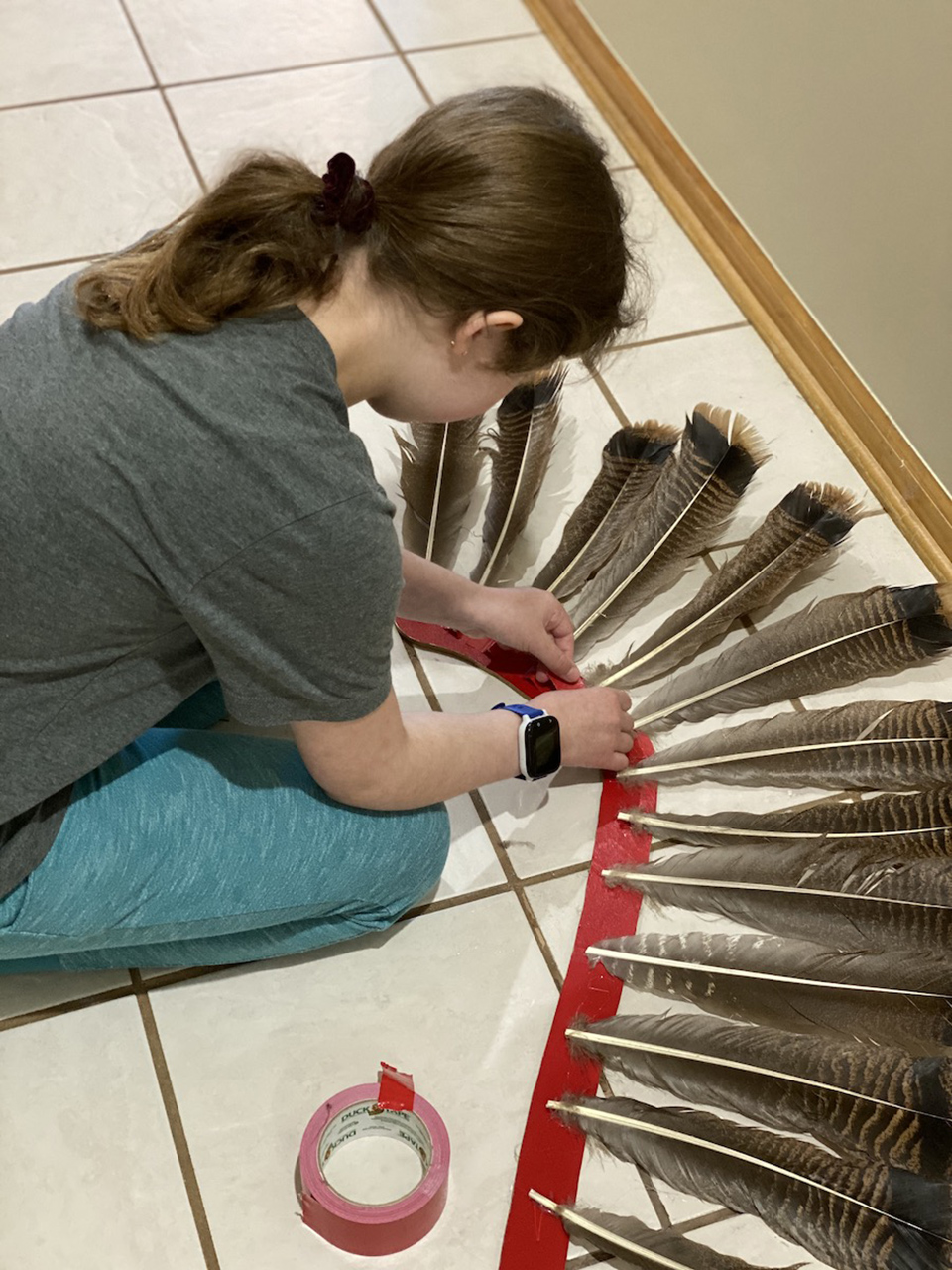 With the feathers glued to the supports, Anna adds duct tape for additonal support