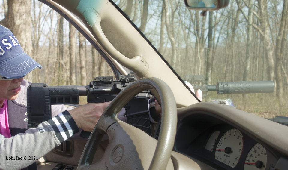 Barb with AR pistol suppressed using truck door and windshield pillar as support