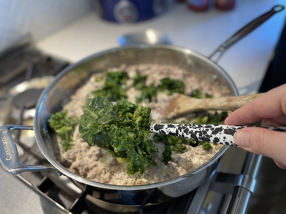 Adding cooked kale to manicotti filling