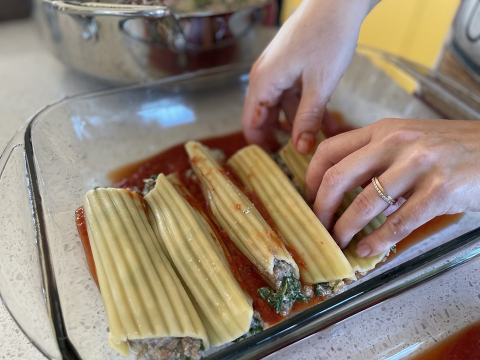 Adding filled manicotti noodles to pan