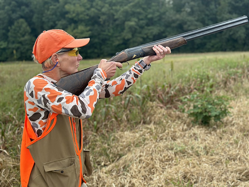 Woman shooting shotgun in field