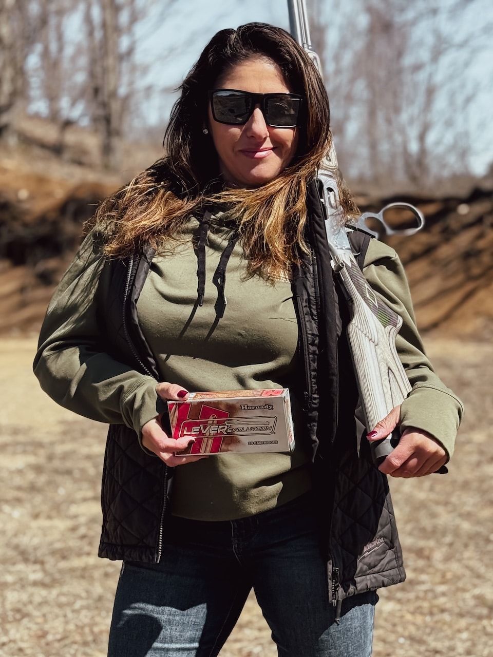 Woman holding rifle and ammunition on a range .45-70