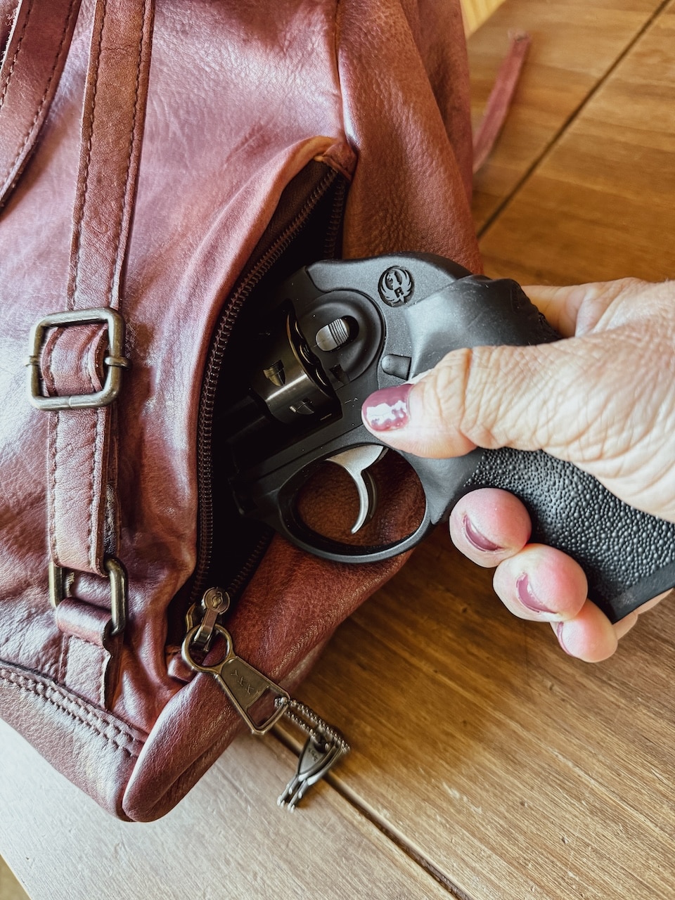 Woman's hand withdrawing a revolver from a cc handbag Concealed Carry